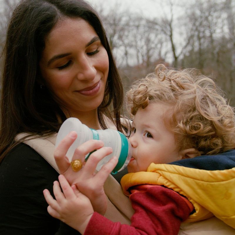 Mom bottle-feeding her child outdoors with the babygami collapsible bottle