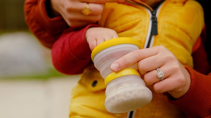Toddler holding the collapsible snack cup with both hands